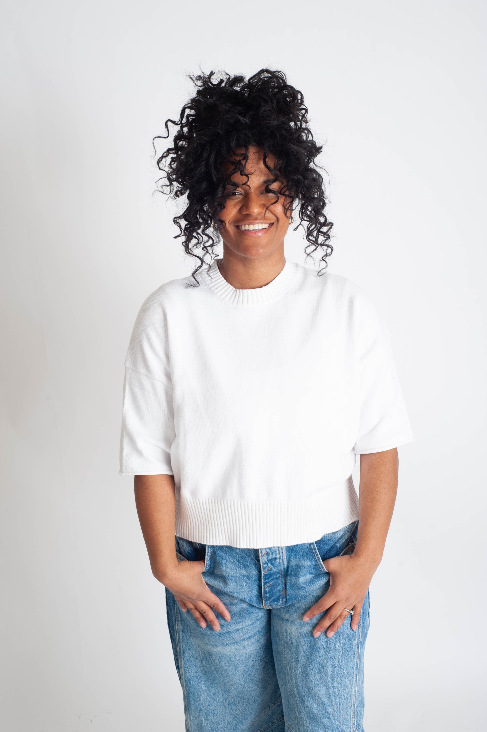 Person wearing a white shirt and blue jeans on a plain background