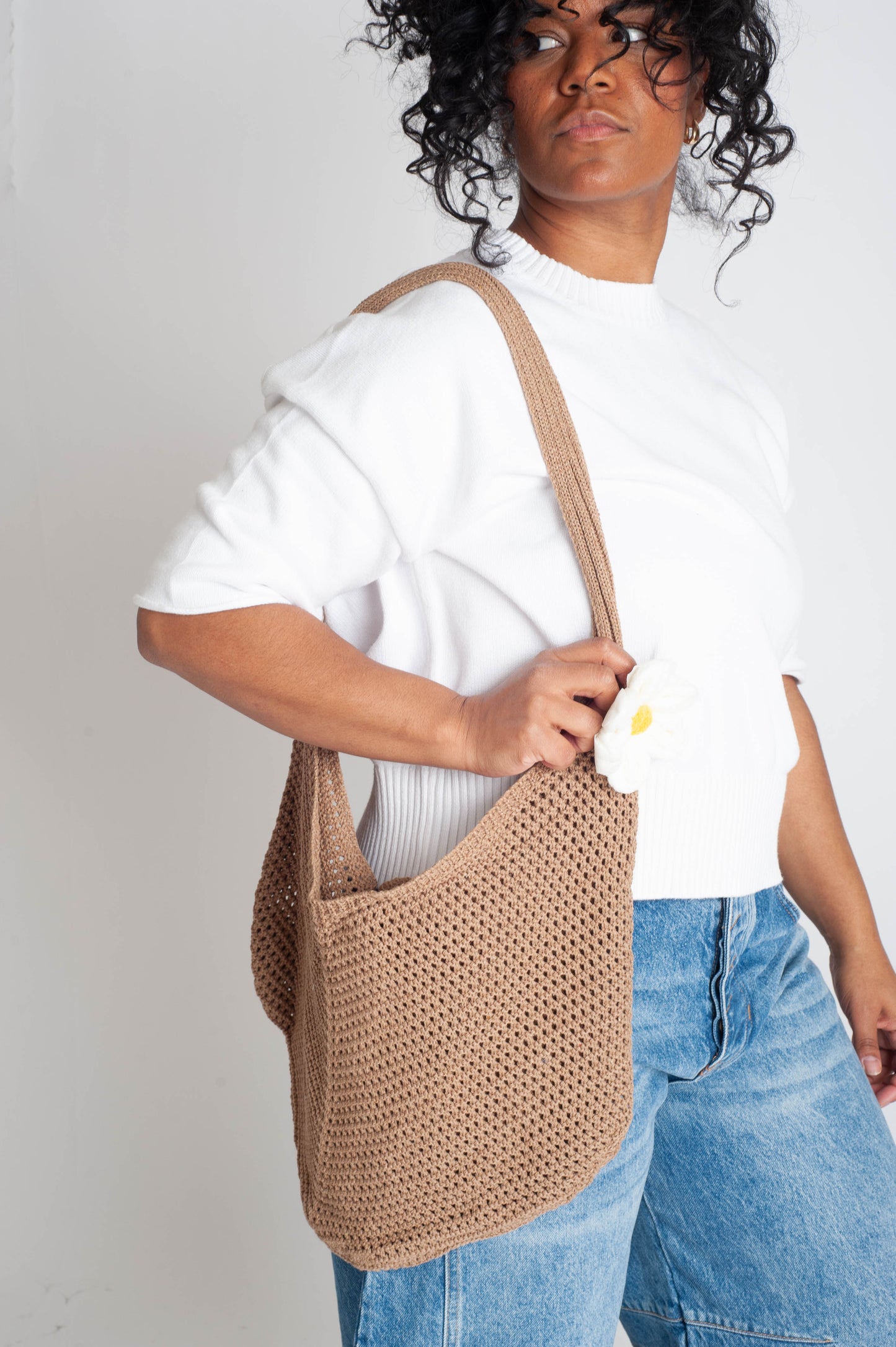 Person holding a beige woven bag against a plain background