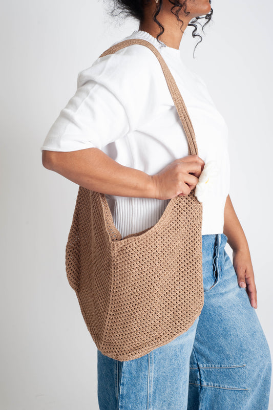 Person holding a beige woven bag against a white background