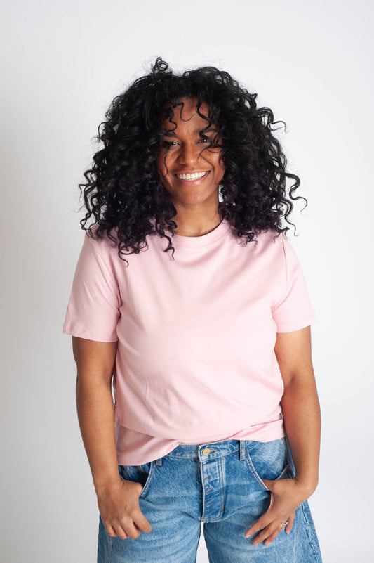 Person wearing a pink t-shirt and blue jeans against a white background