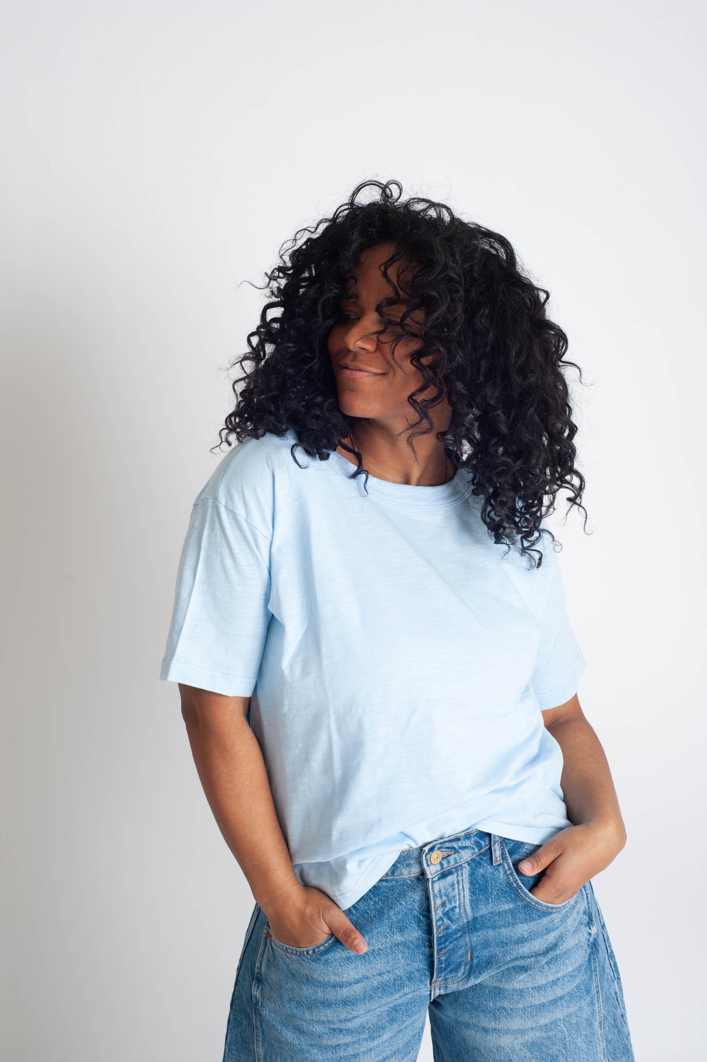 Person wearing a light blue t-shirt and jeans against a plain background