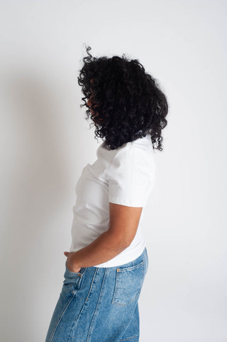 Person wearing a white t-shirt and blue jeans against a plain background