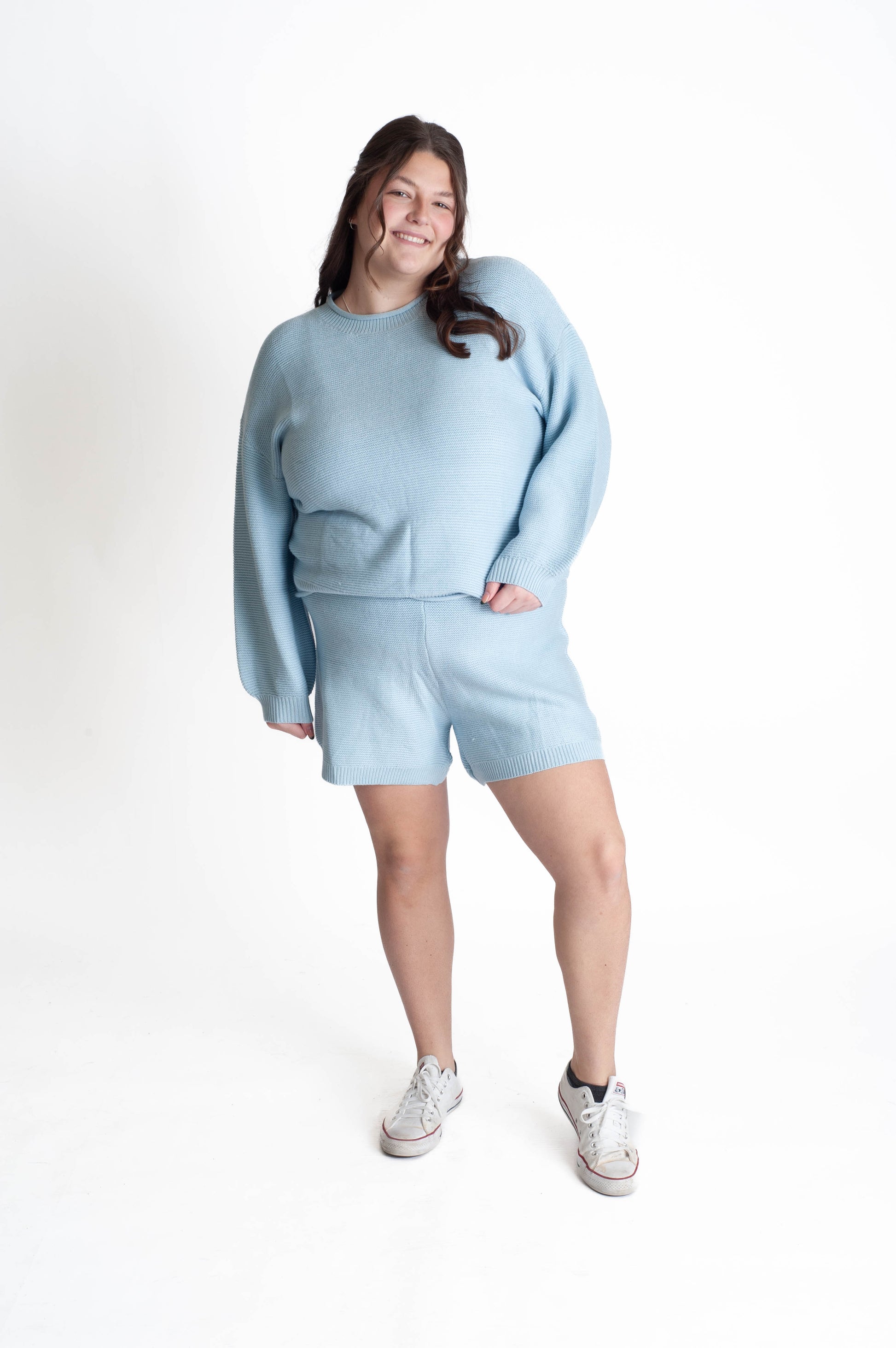 Person wearing a light blue sweater and shorts set on a white background