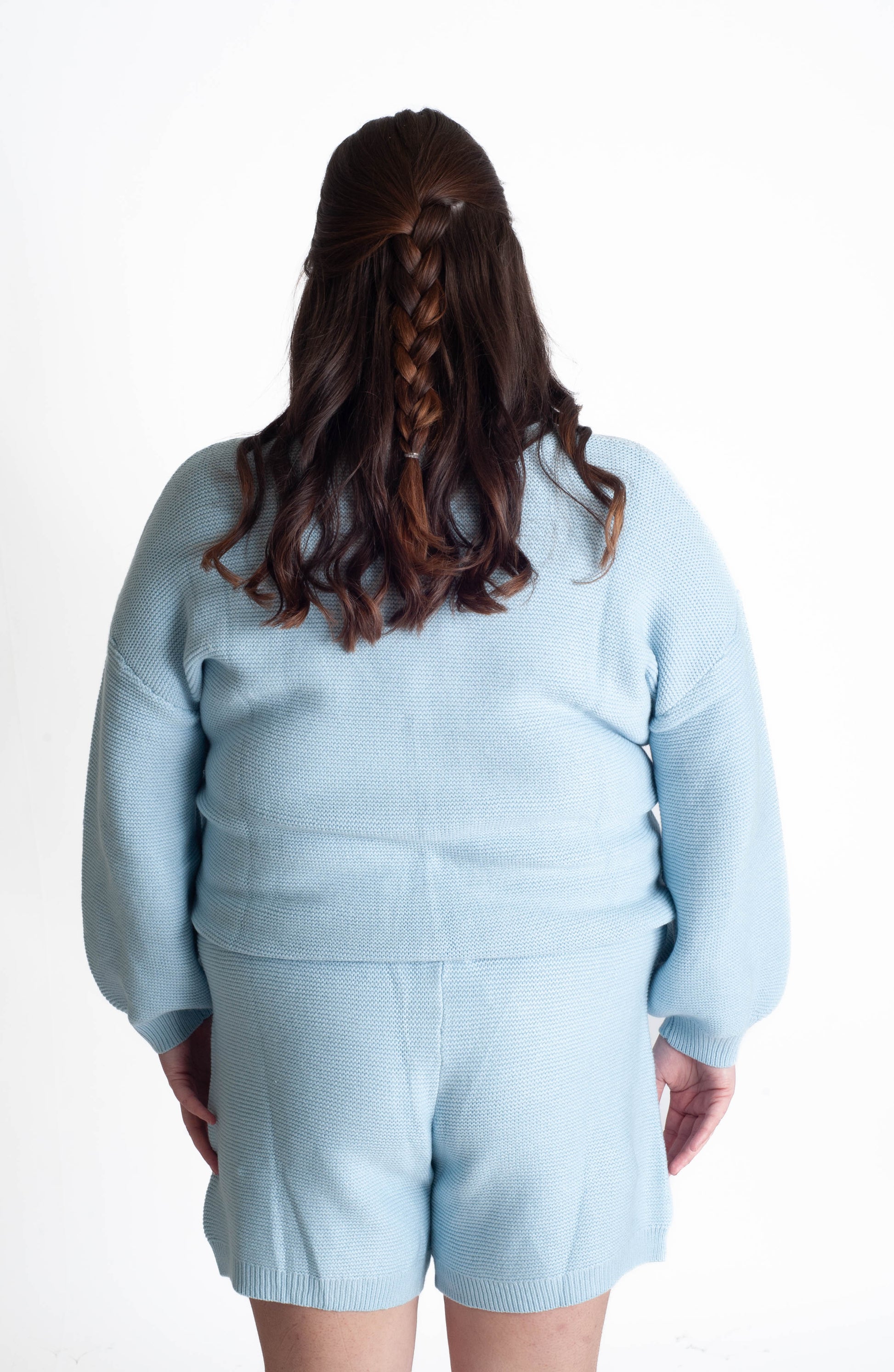 Person wearing a light blue outfit with shorts on a white background