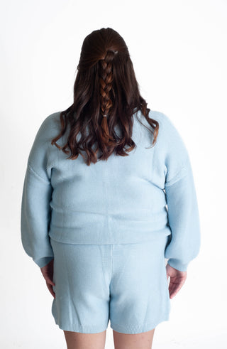 Person wearing a light blue outfit with shorts on a white background