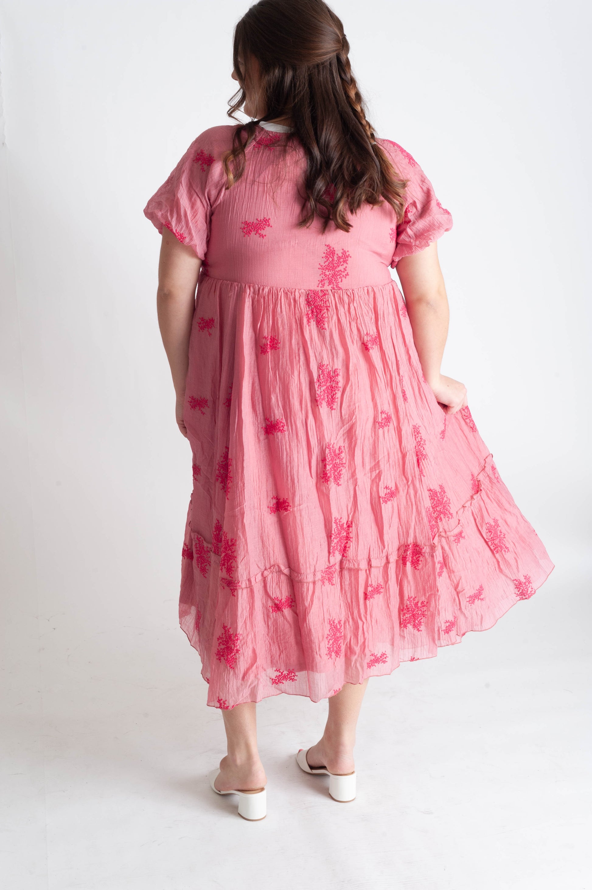 Young girl wearing a pink floral dress on a white background