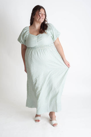 Woman wearing a green and white striped dress on a white background