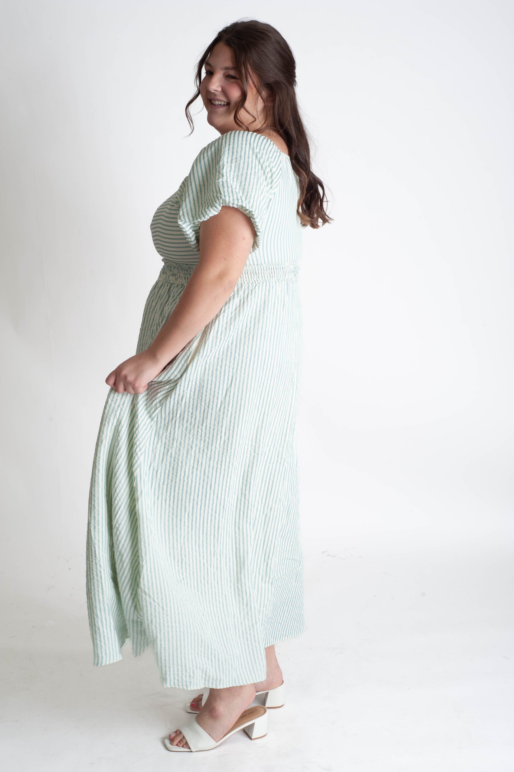Woman wearing a green and white striped dress on a white background