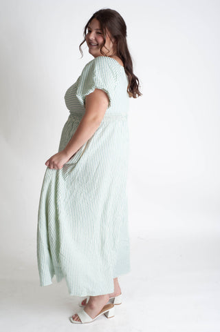 Woman wearing a green and white striped dress on a white background