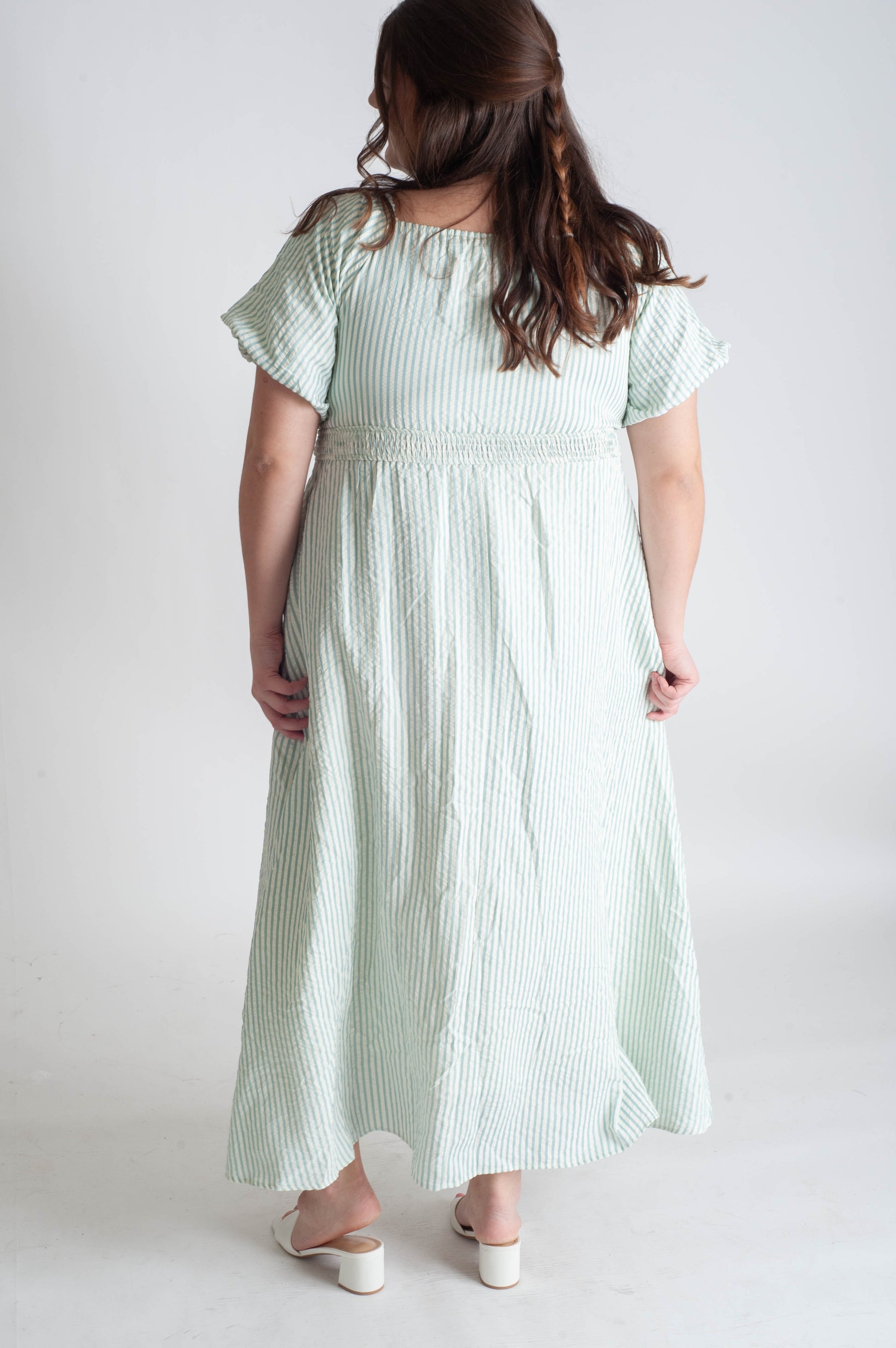 Woman wearing a light green striped dress on a white background