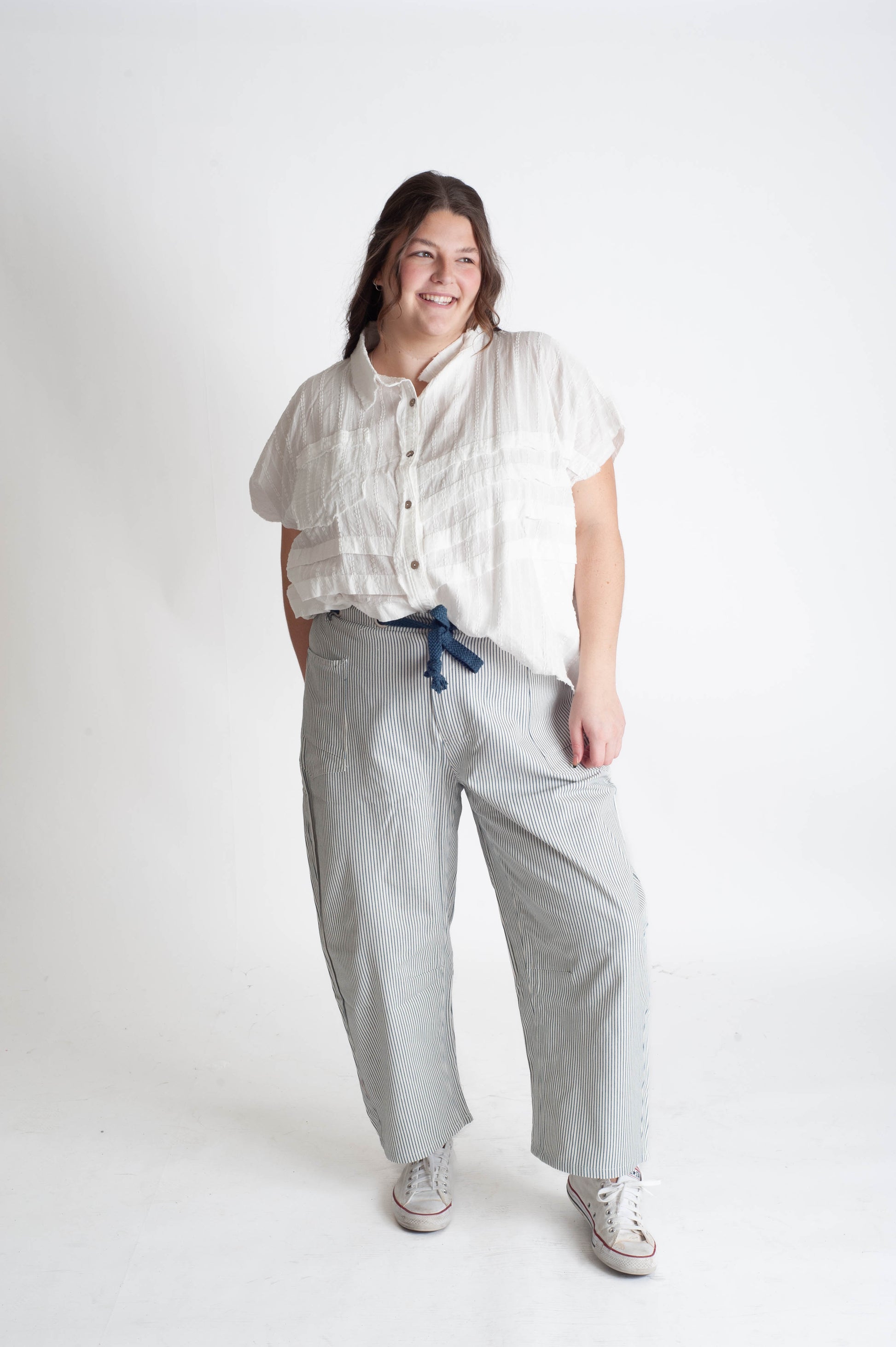 Person wearing a white shirt and light gray pants on a white background