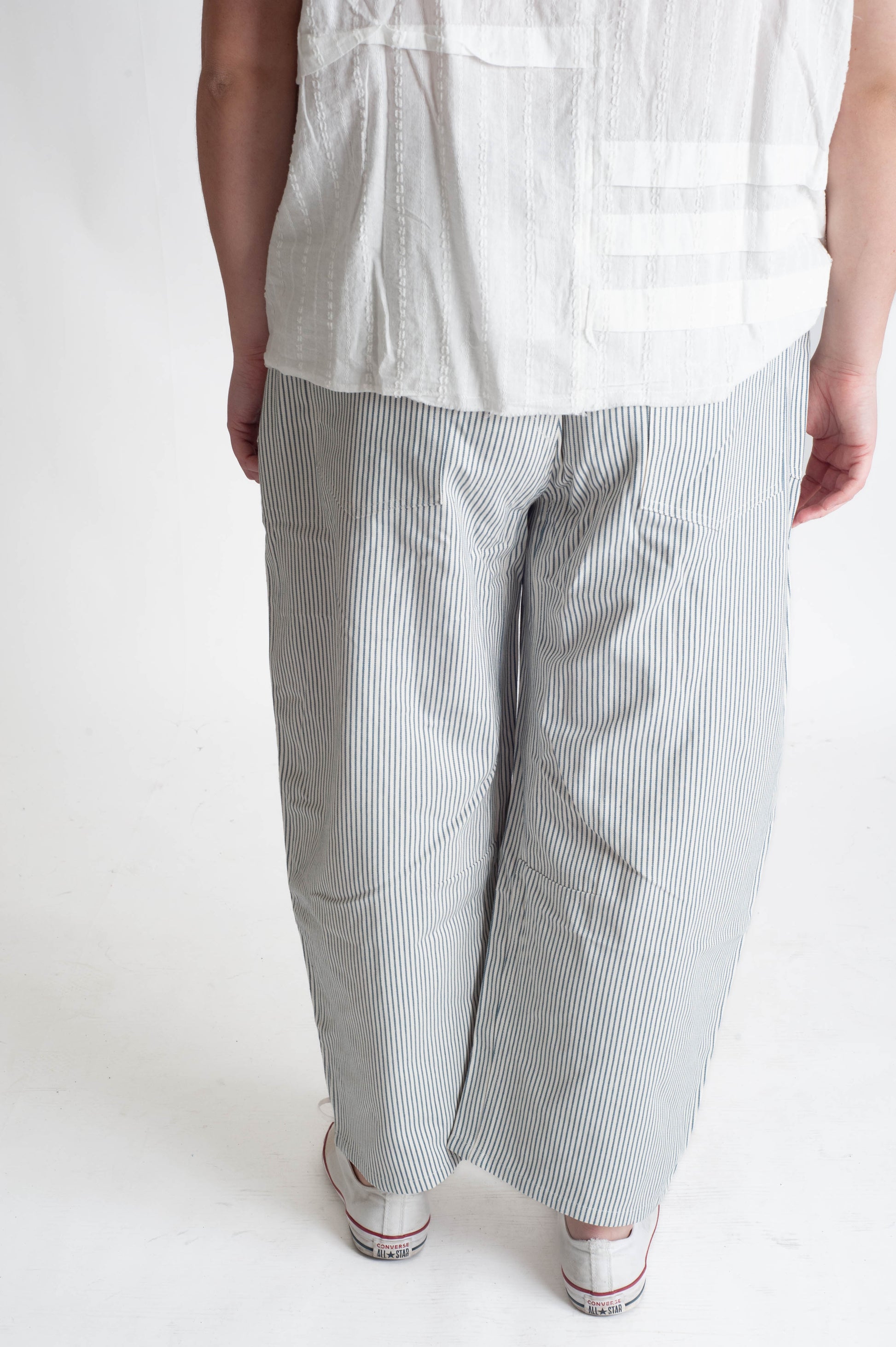 Person wearing a white shirt and gray striped pants on a white background