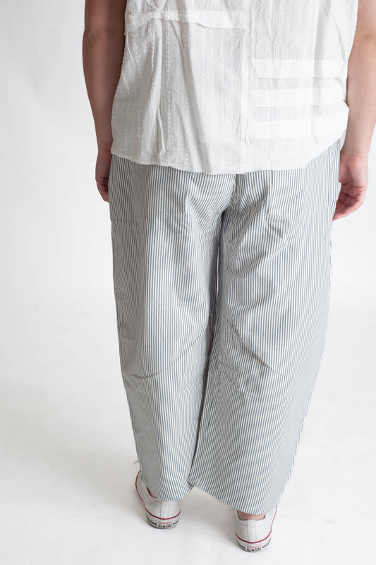 Person wearing a white shirt and gray striped pants on a white background