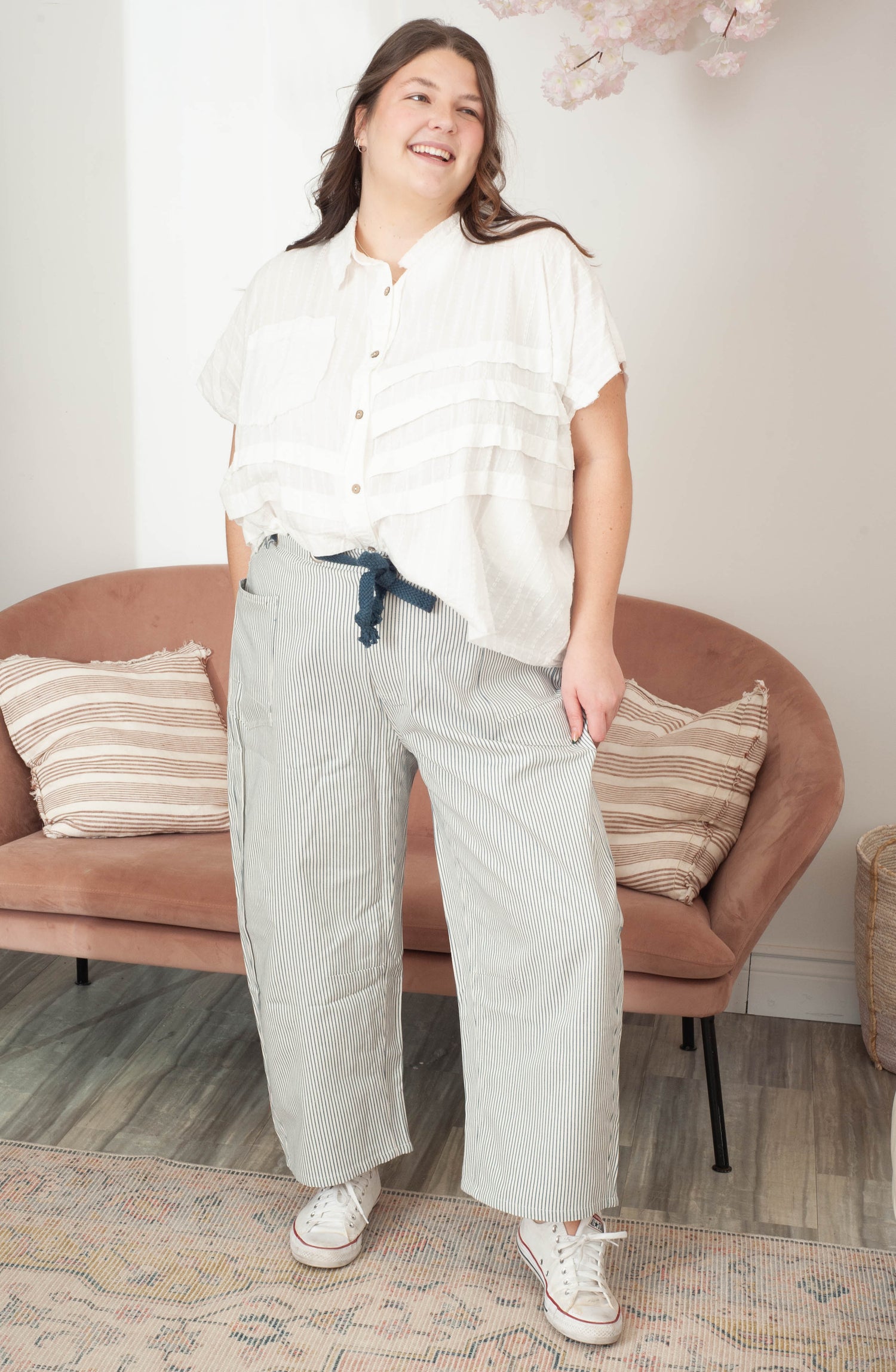 Women wearing blue stripe barrel pants and a white blouse in a living room. 