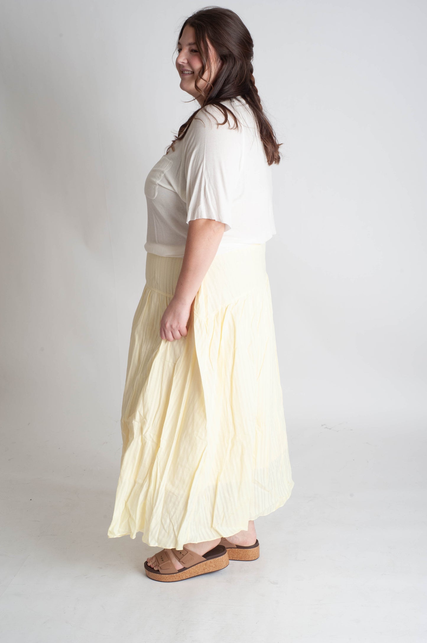 Woman wearing a white top and light yellow skirt on a white background