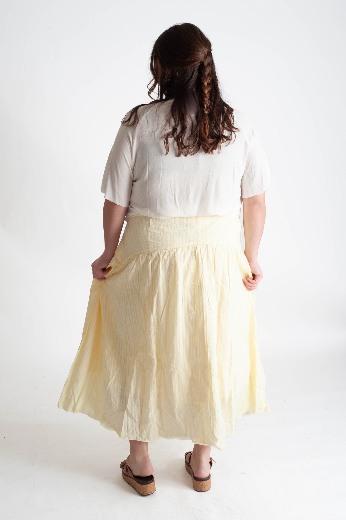 Woman wearing a white blouse and yellow skirt on a white background