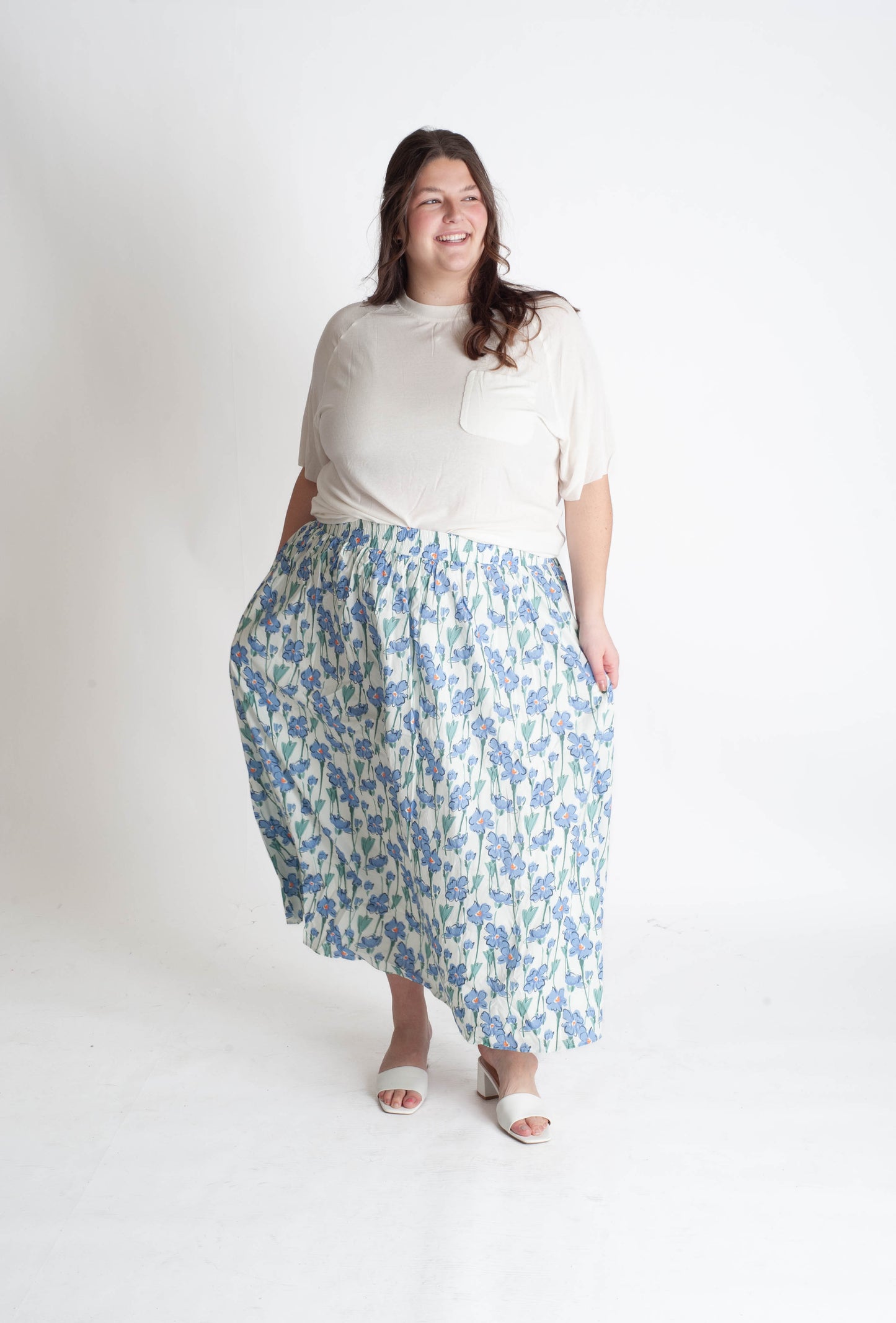 Woman wearing a white top and blue floral skirt on a white background
