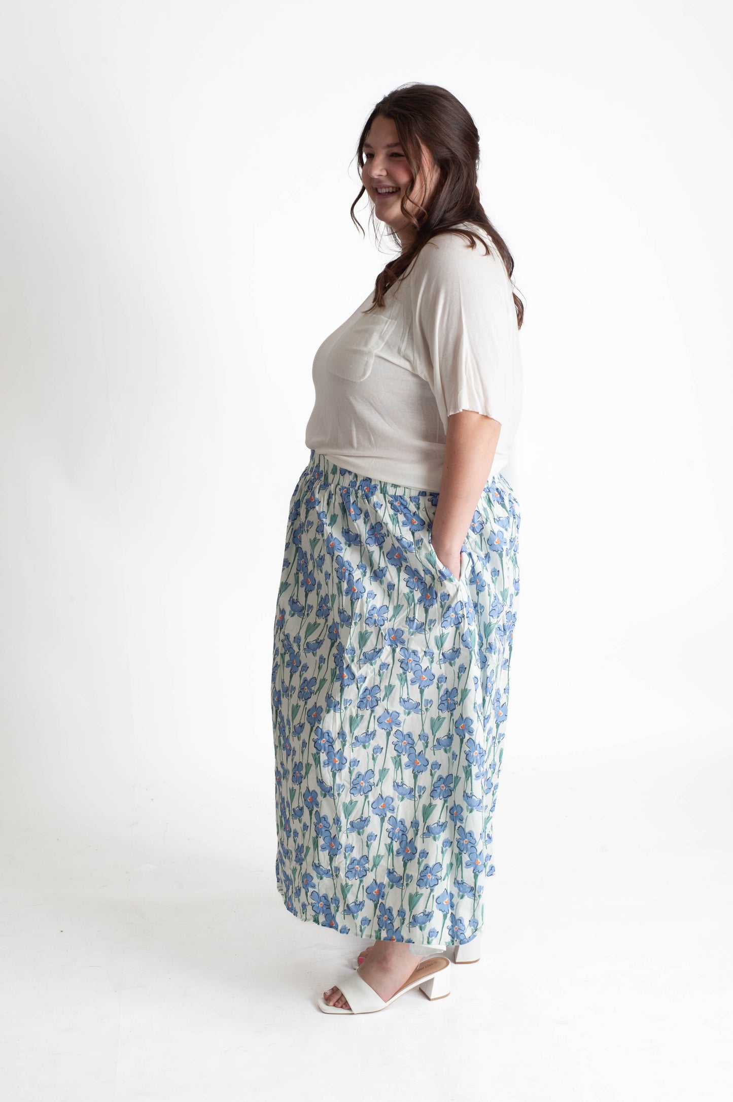 Woman wearing a white top and floral skirt on a white background