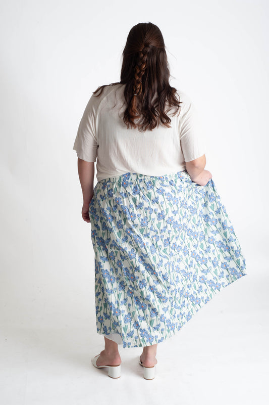 Person wearing a white t-shirt and floral skirt on a white background