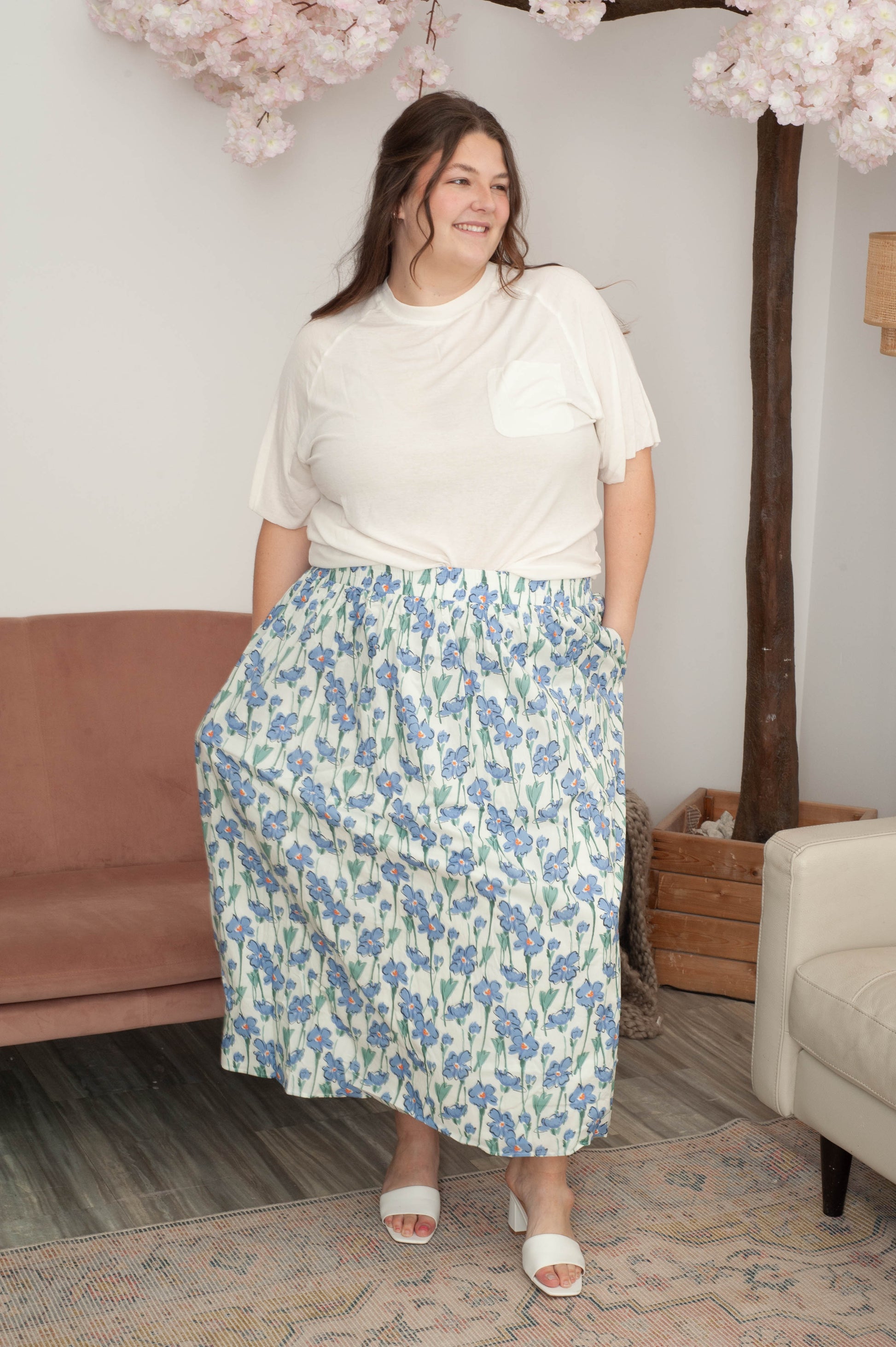 Woman wearing a floral skirt and white top in a living room setting