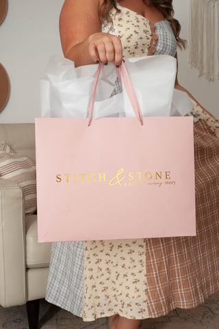 Woman in dress holding a pink shopping bag. 