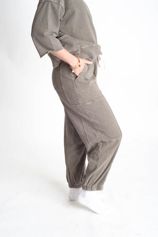 Person wearing a gray jumpsuit on a white background