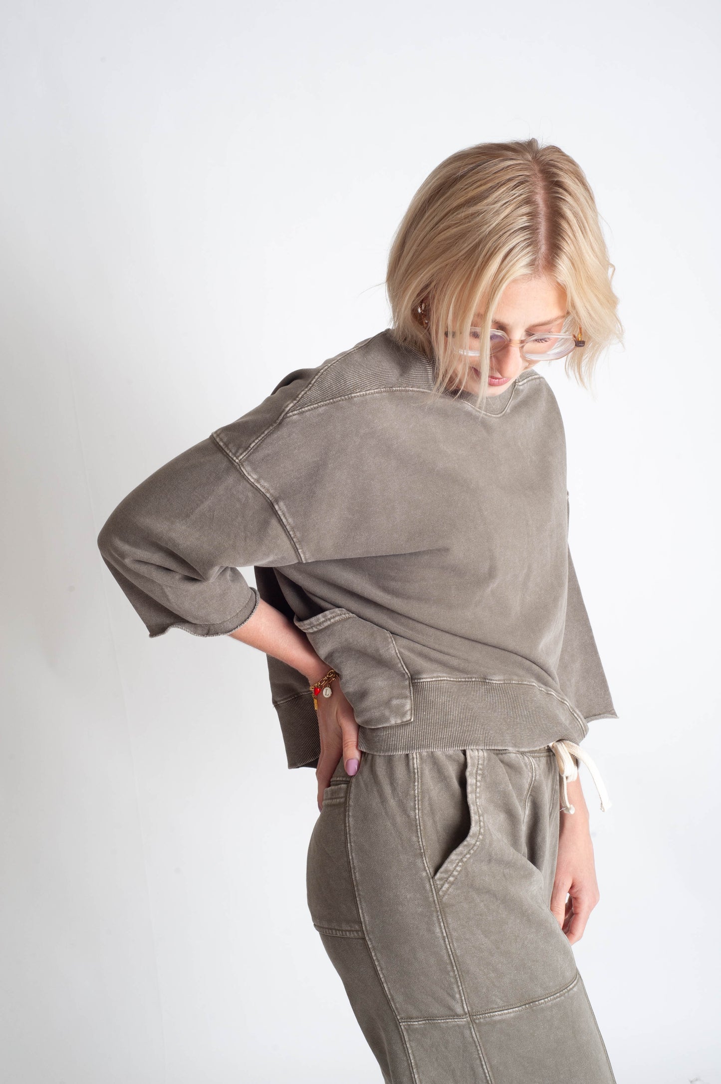 Person wearing a green sweater and pants on a white background