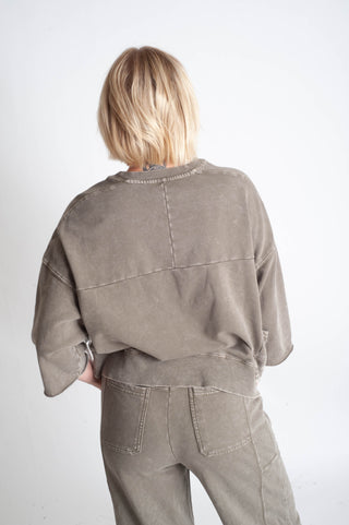 Person wearing a beige jacket and pants on a white background