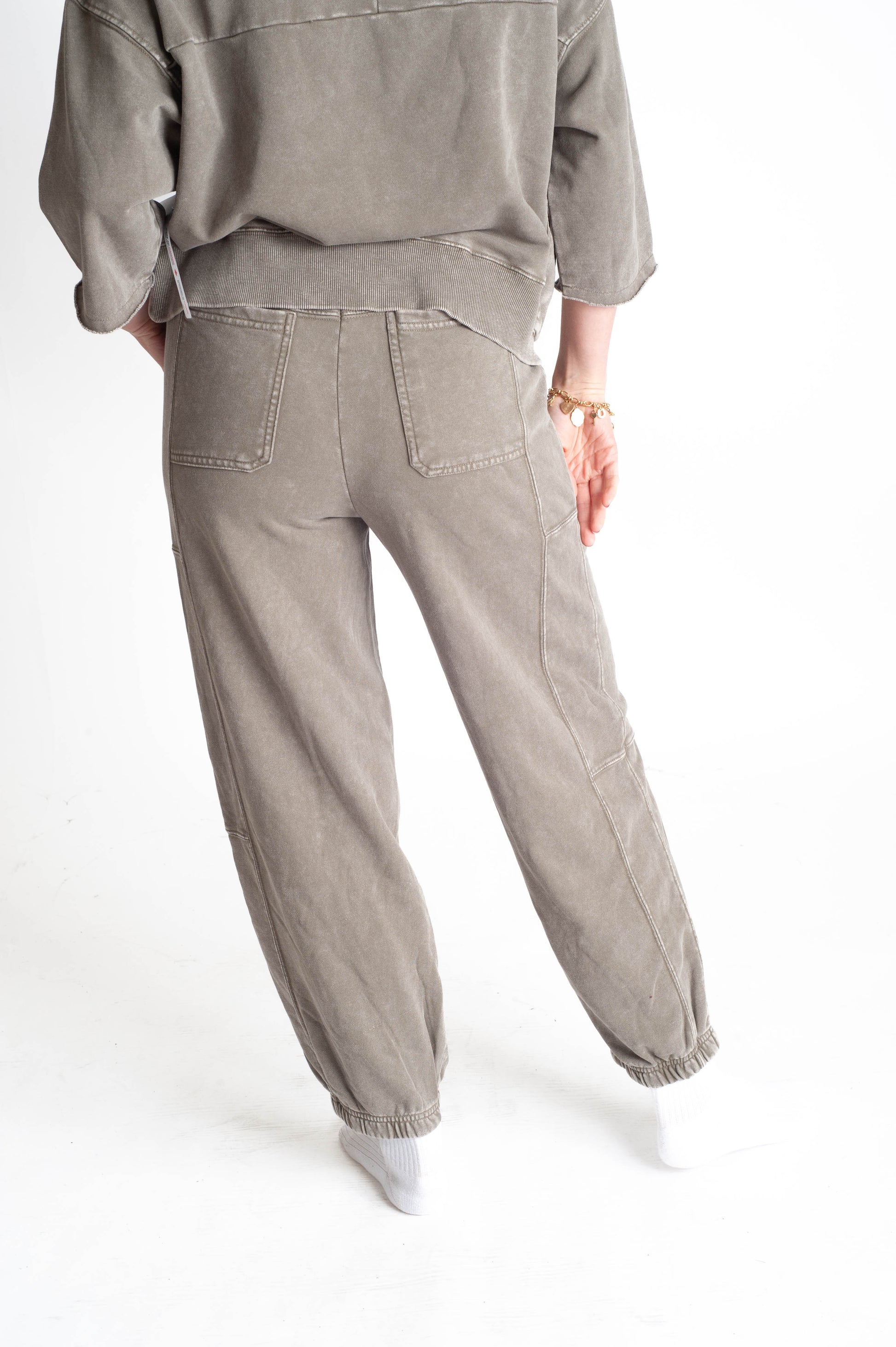Person wearing a gray outfit with pants on a white background