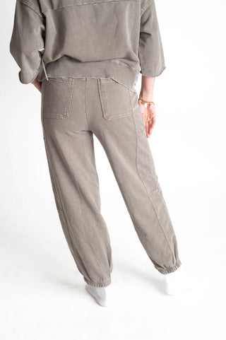 Person wearing a gray outfit with pants on a white background