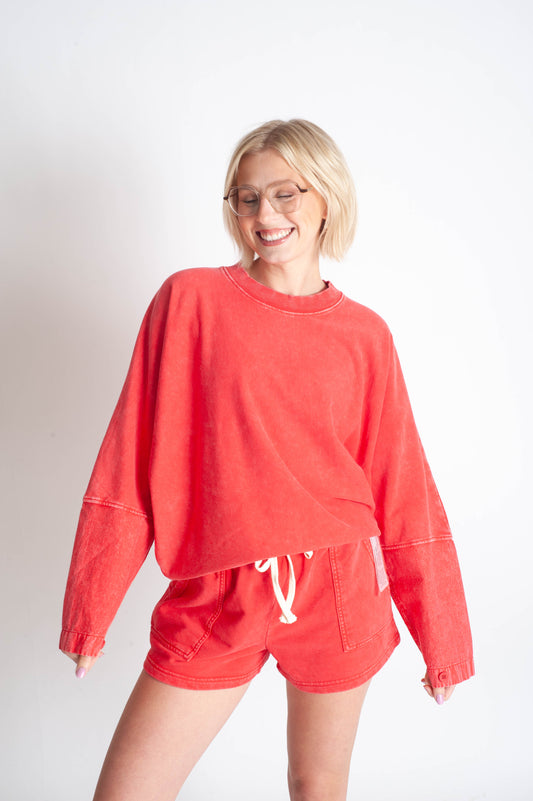 Person wearing a red sweatshirt and shorts set on a white background