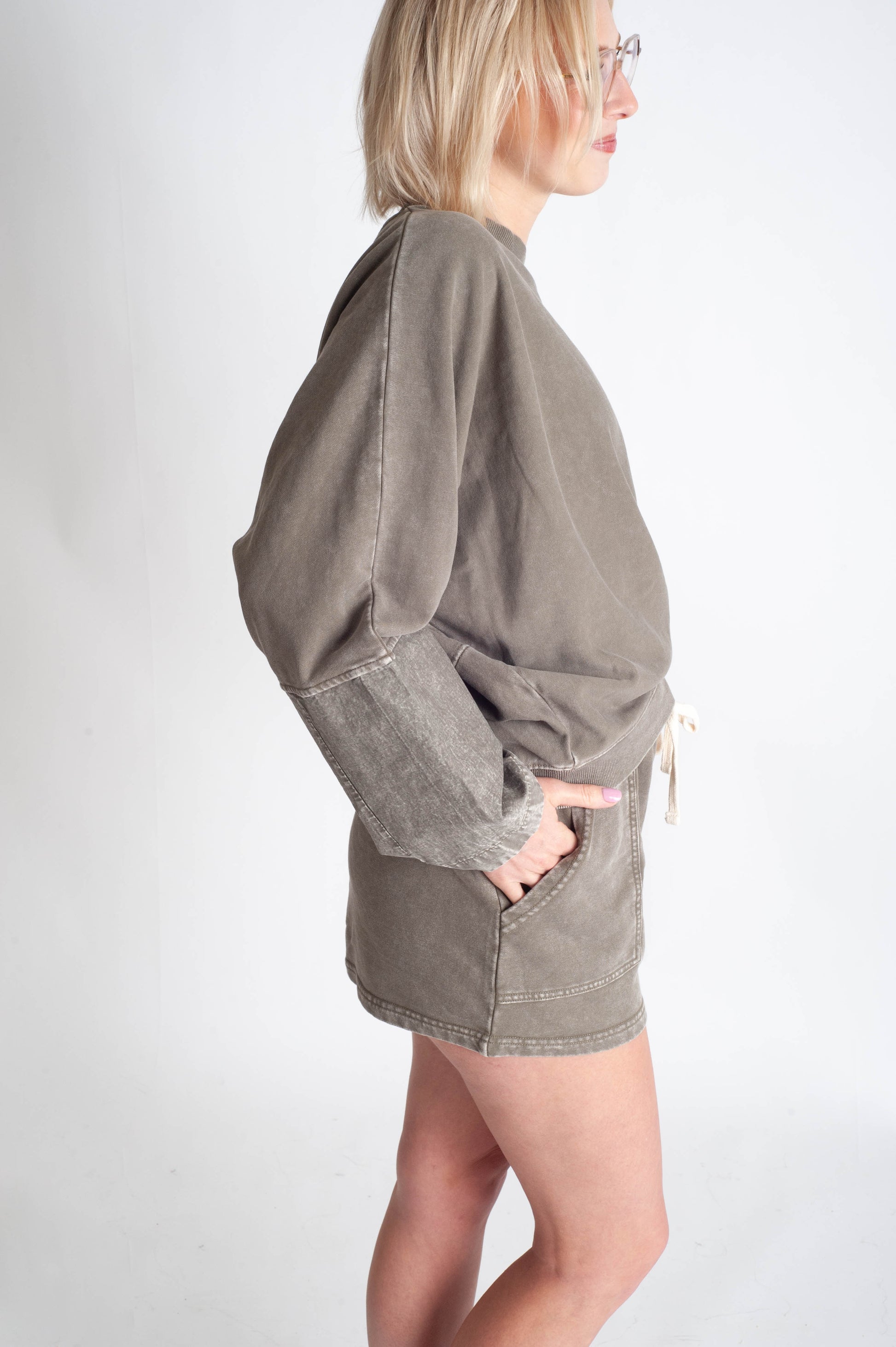Person wearing a gray oversized sweatshirt on a white background
