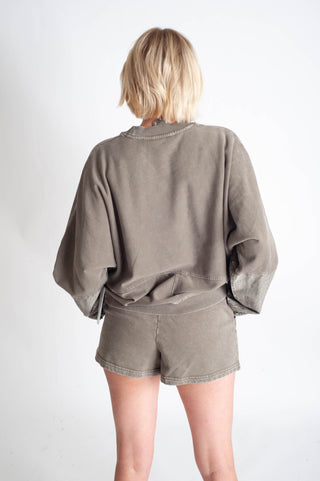 Person wearing a green oversized shirt and shorts set on a white background