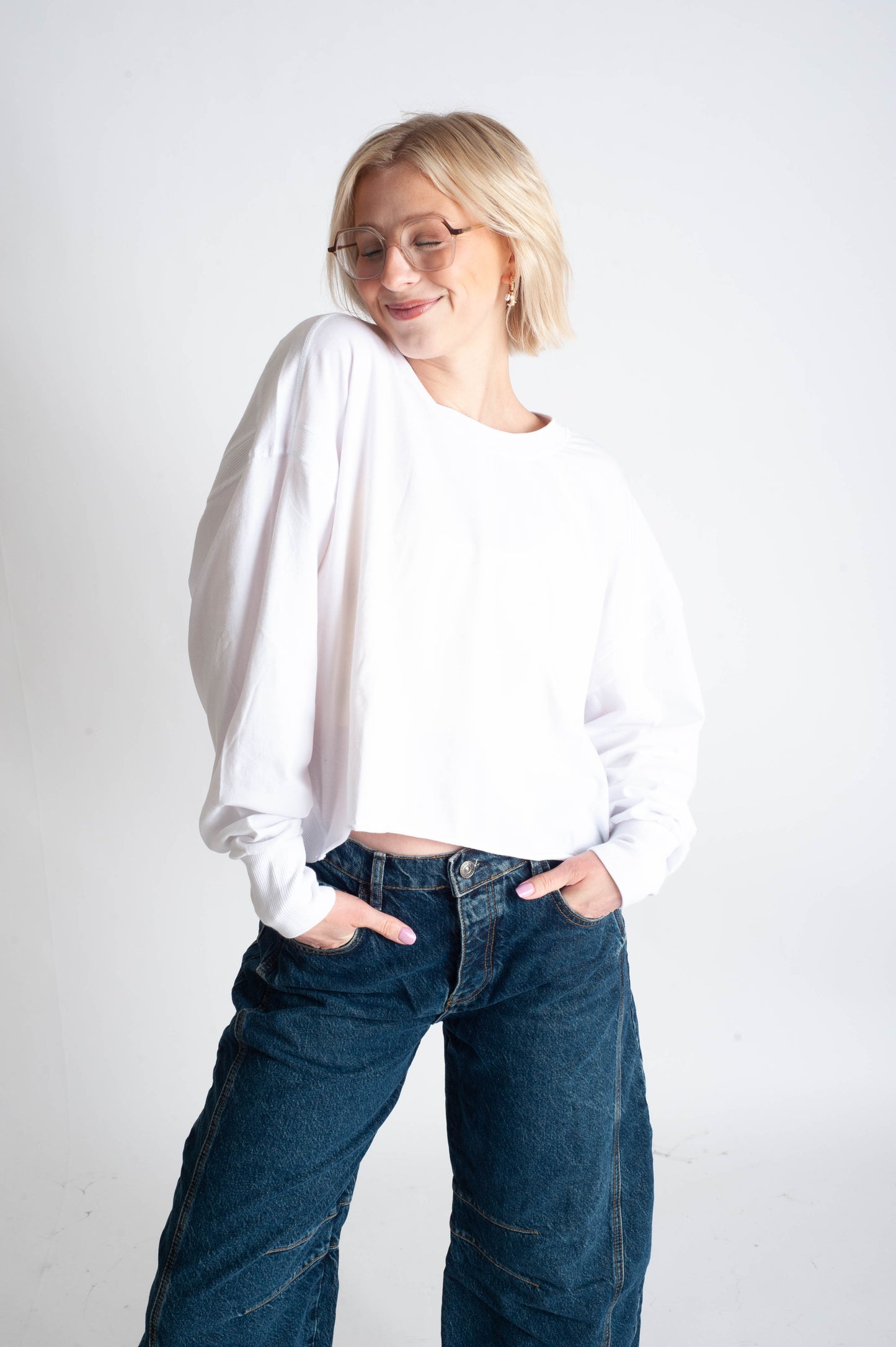 Person wearing a white shirt and blue jeans on a plain background