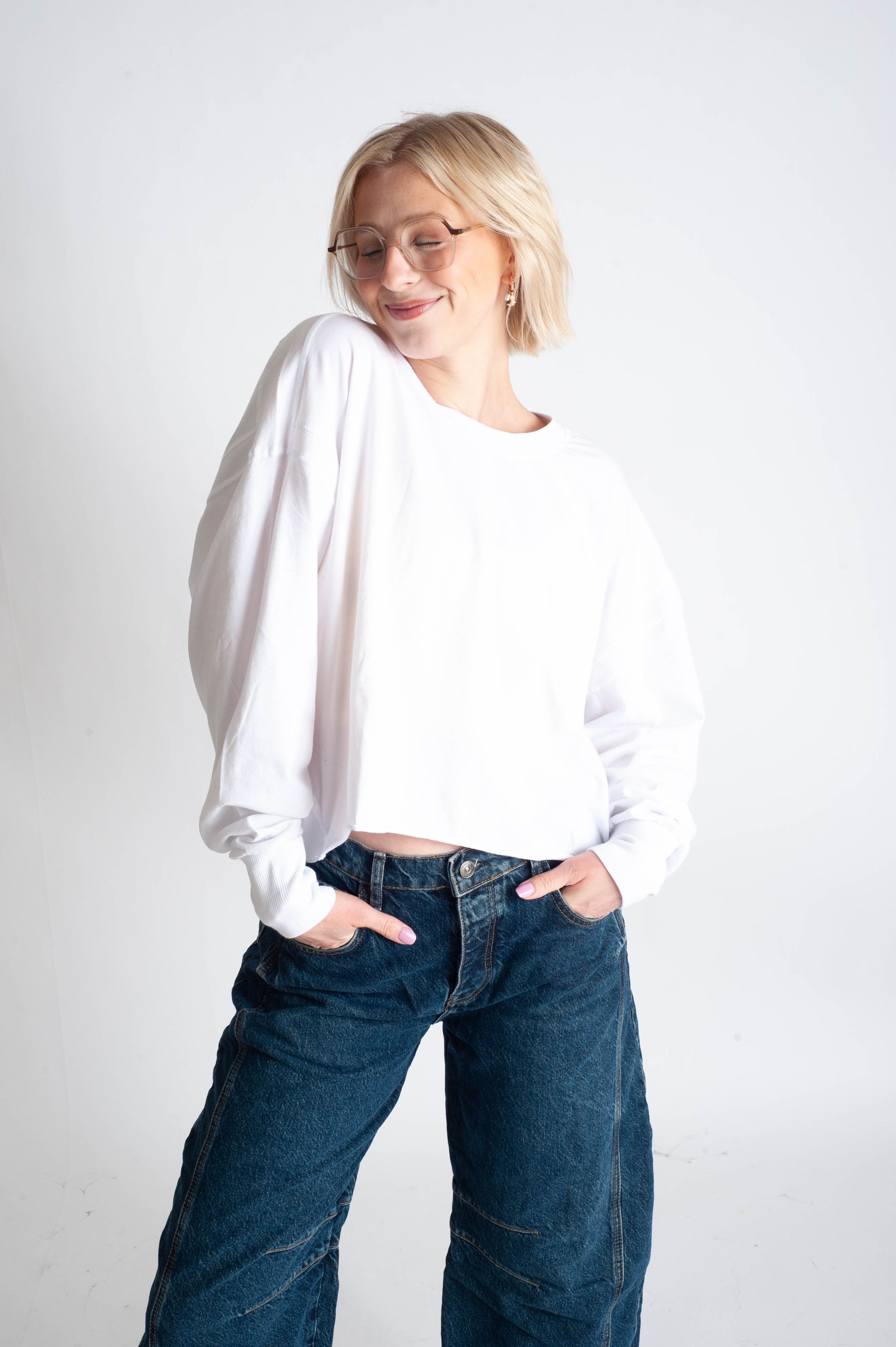 Person wearing a white shirt and blue jeans on a plain background