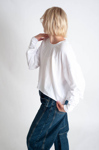 Person wearing a white sweater and blue jeans against a white background
