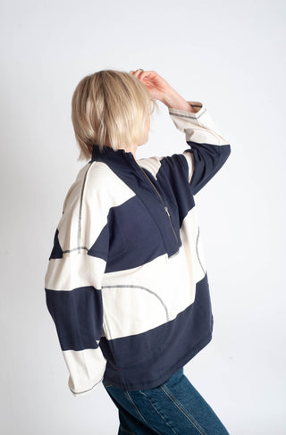Person wearing a navy and white striped jacket on a plain background
