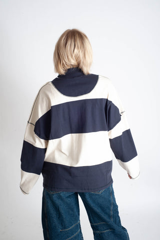 Person wearing a navy and white striped sweater with a hood on a plain background