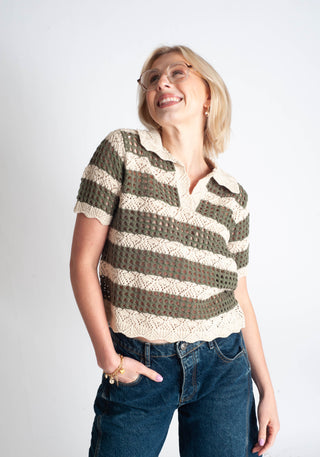 Woman wearing a striped shirt with crochet details on a plain background