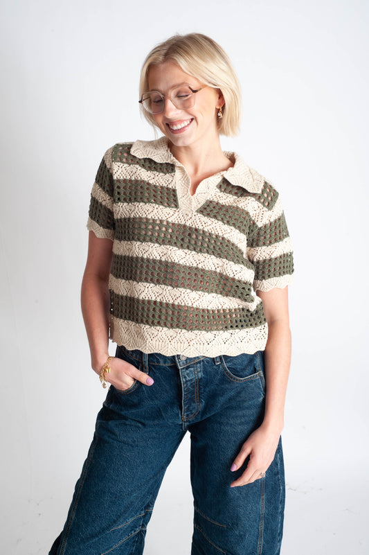 Woman wearing a striped crochet shirt and jeans on a white background