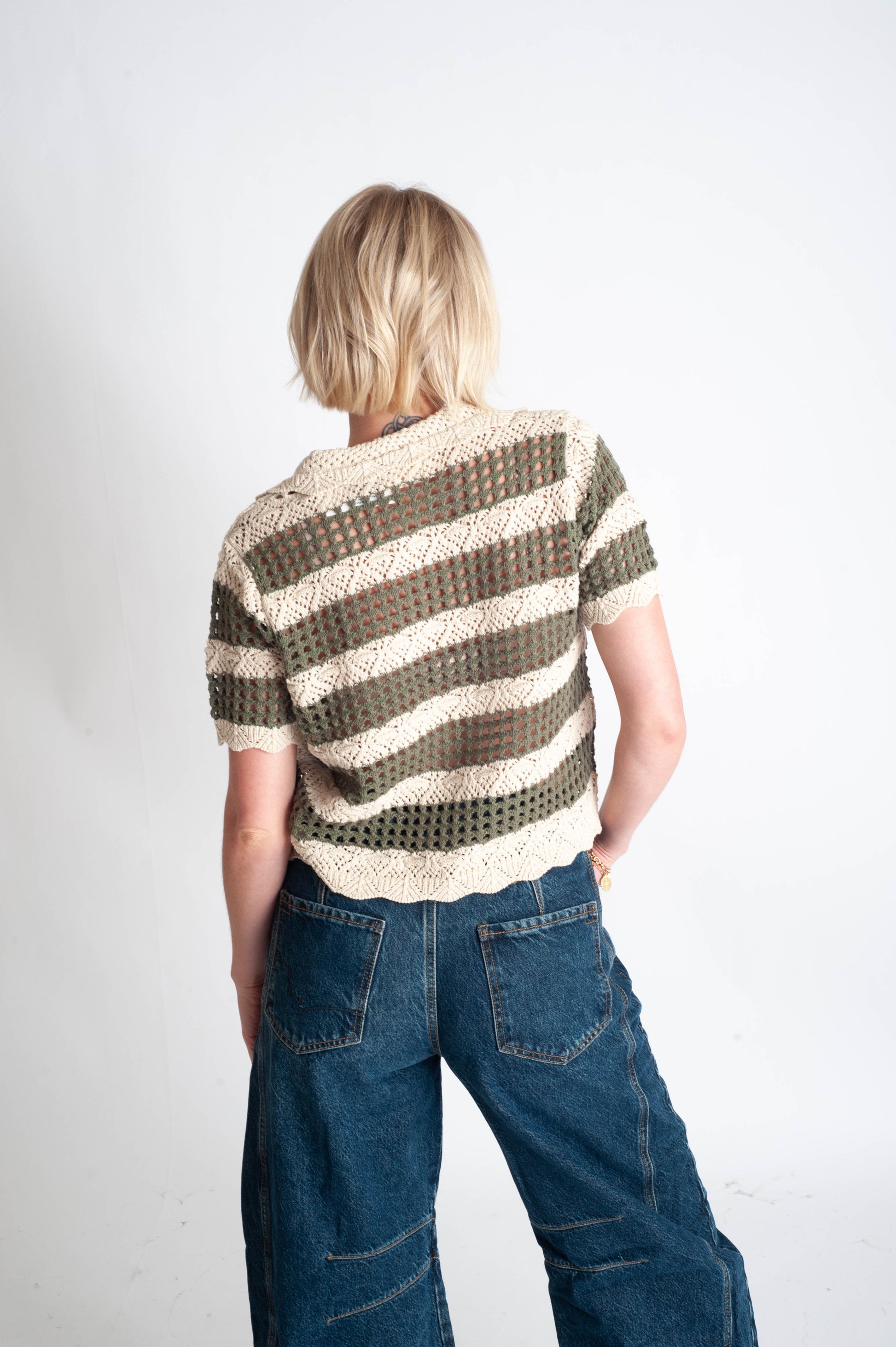Person wearing a striped sweater and blue jeans on a white background