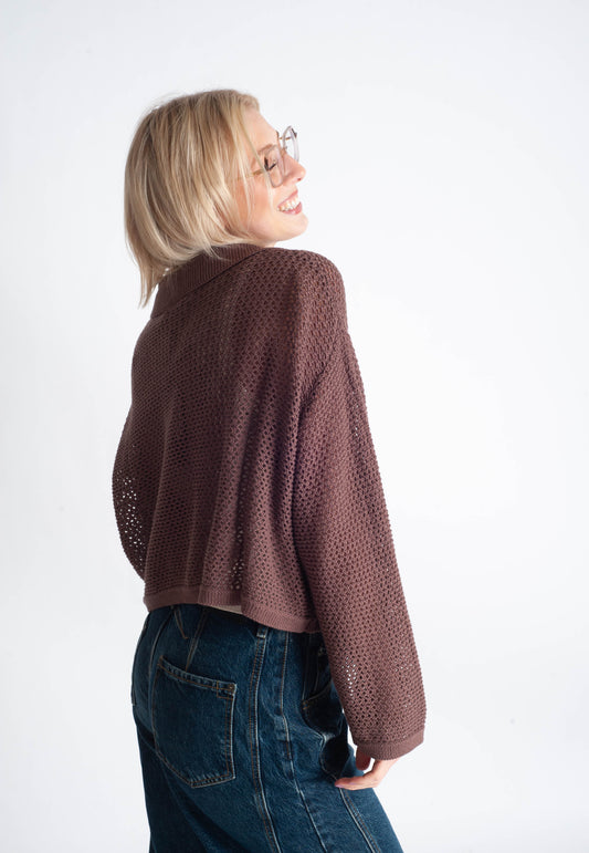 Woman wearing a brown knitted sweater and blue jeans on a white background