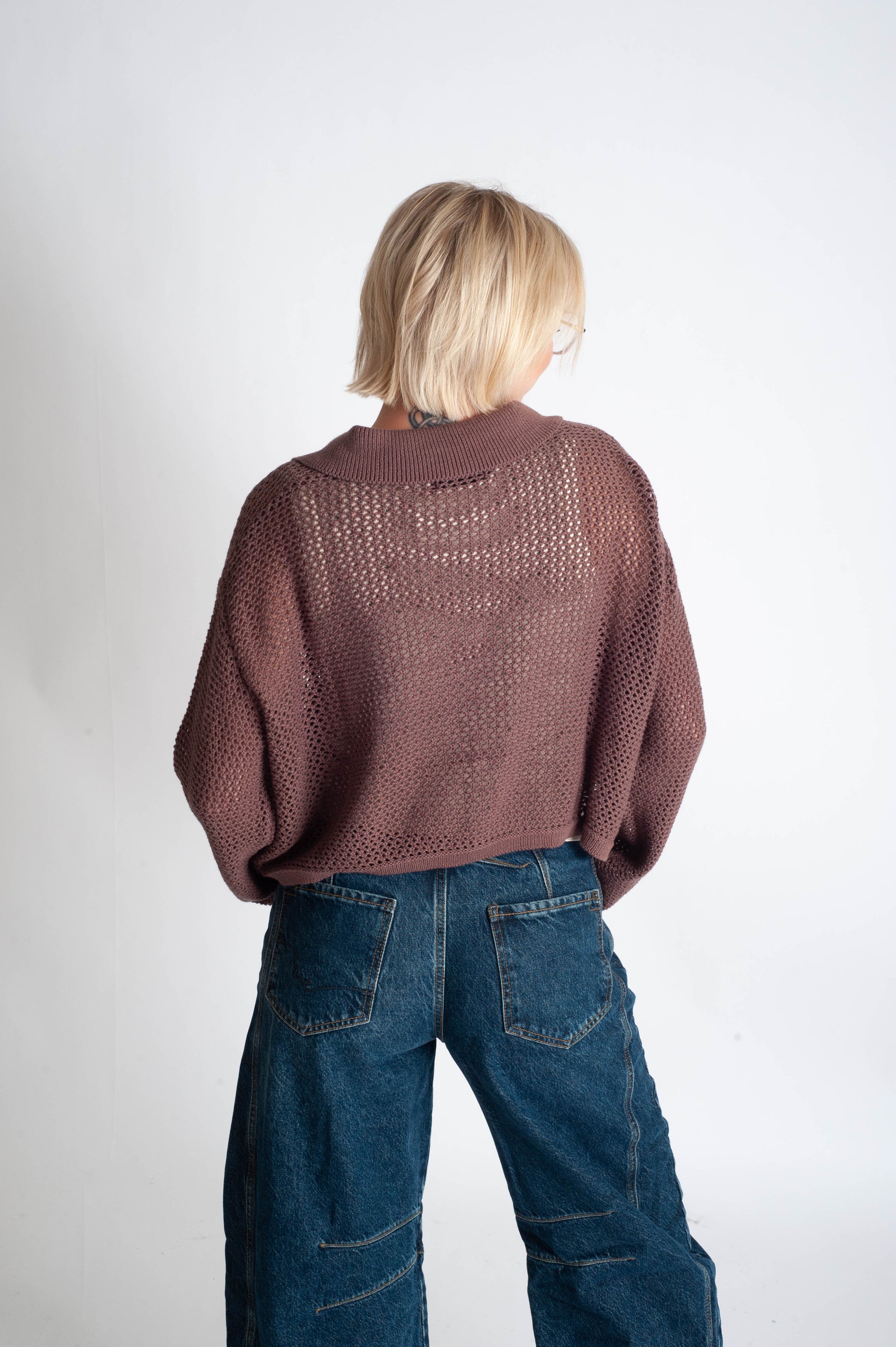 Person wearing a brown sweater and blue jeans on a white background