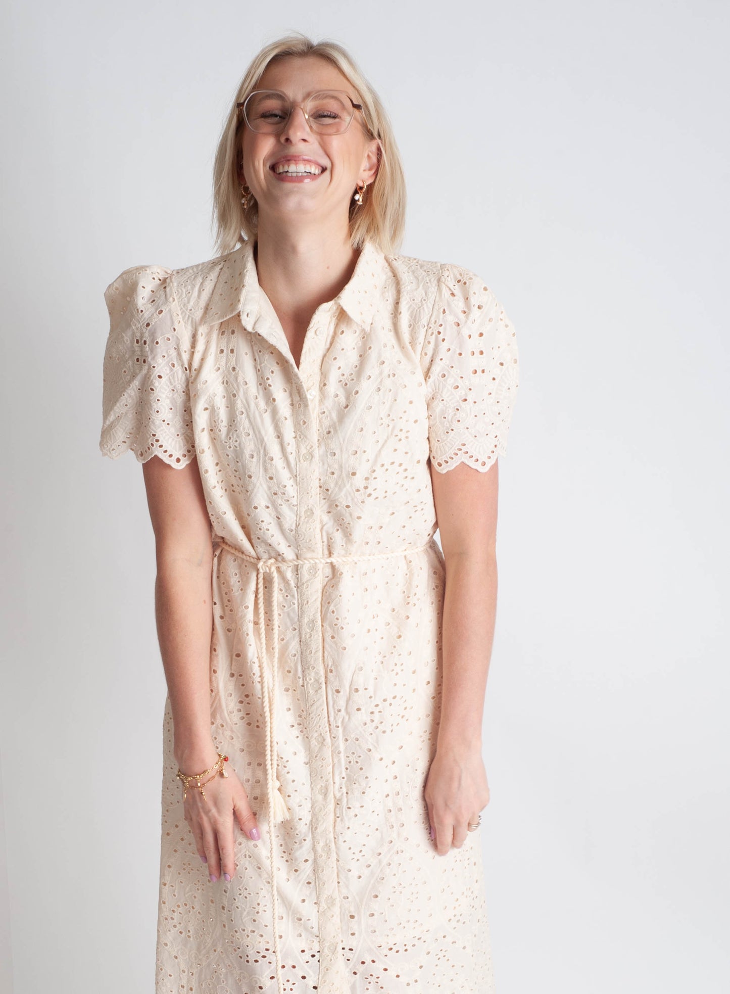 Woman wearing a beige dress with a subtle pattern on a plain background