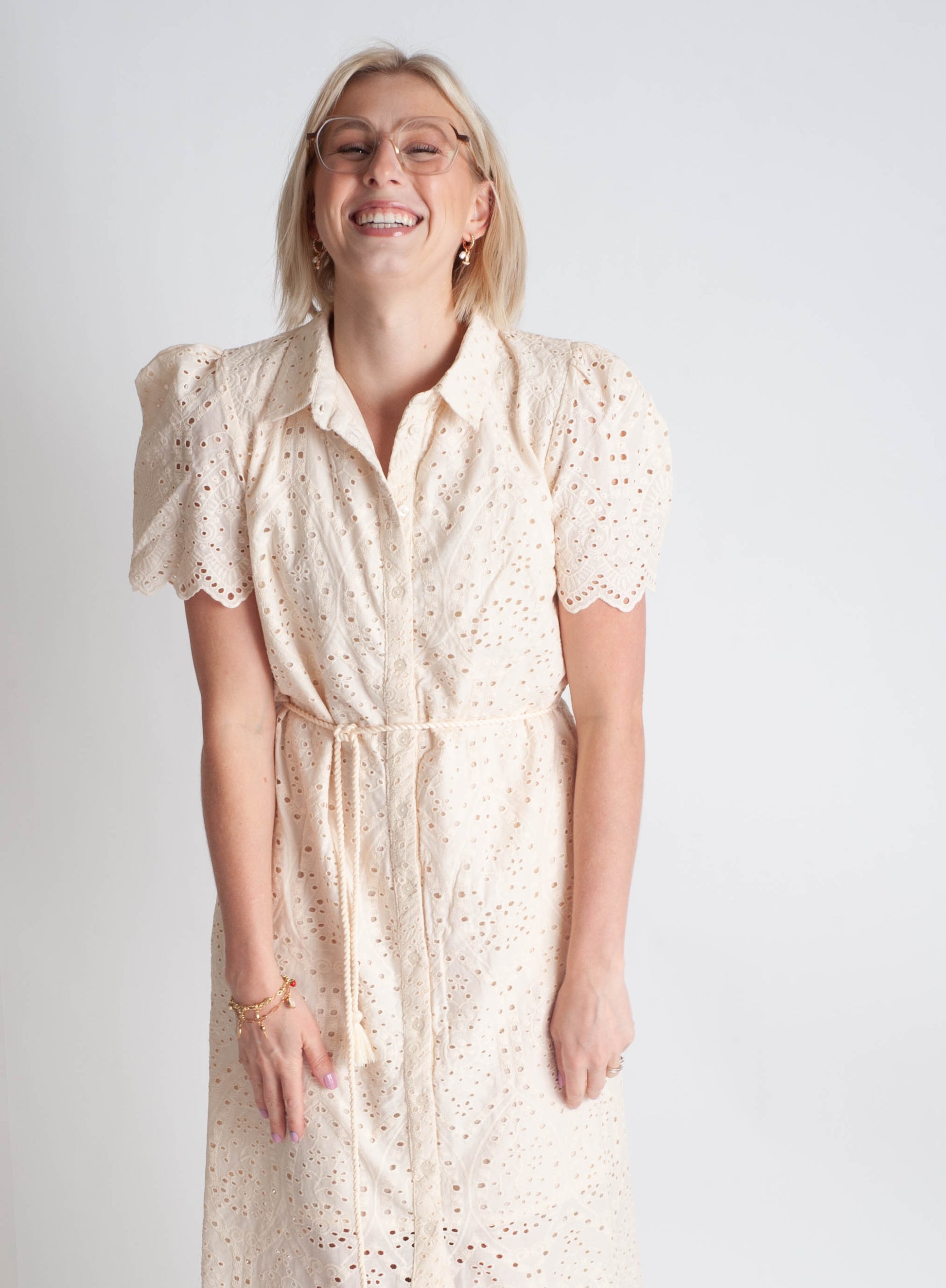 Woman wearing a beige dress with a subtle pattern on a plain background