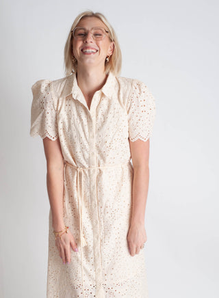 Woman wearing a beige dress with a subtle pattern on a plain background