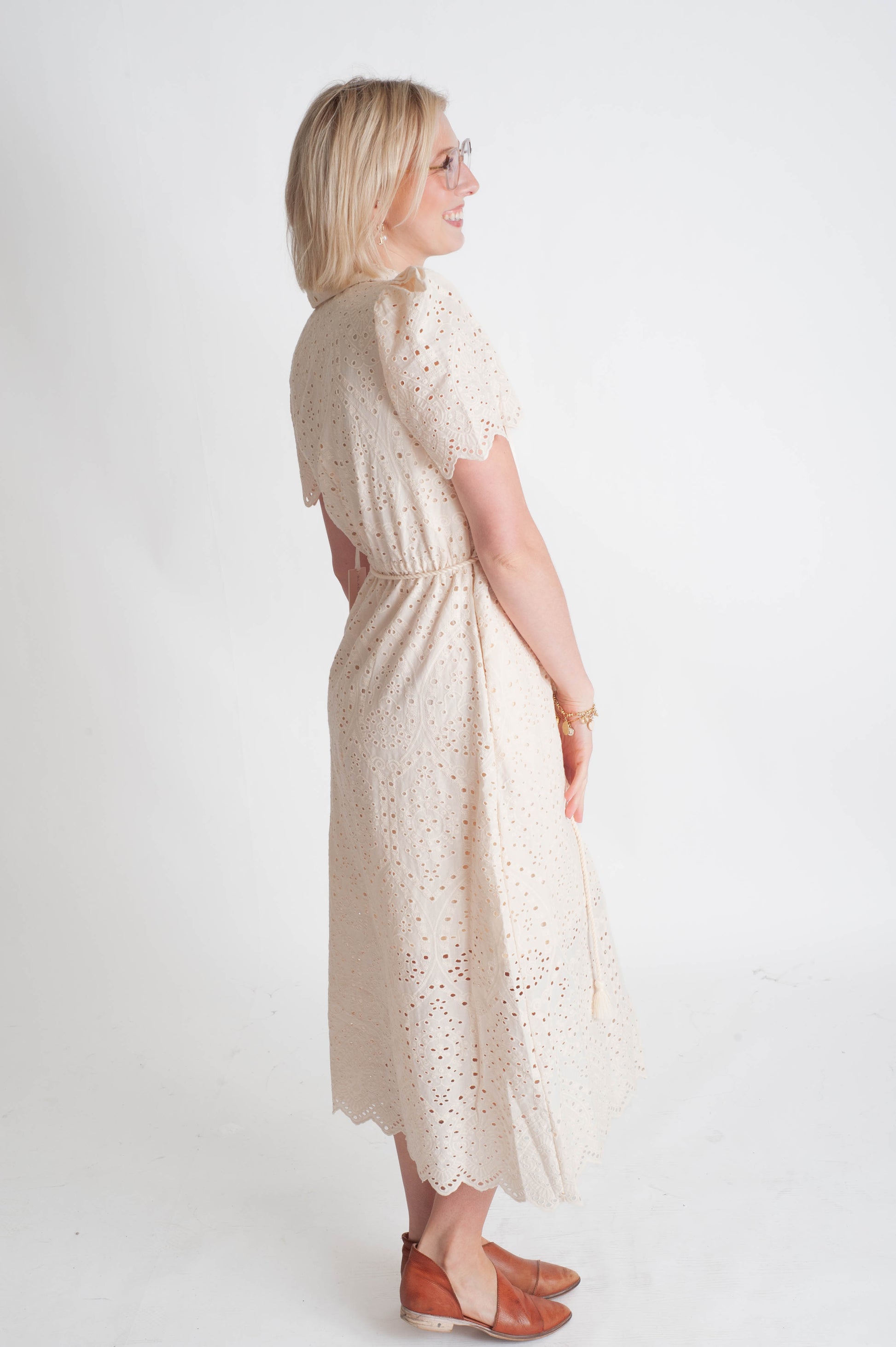 Woman wearing a white lace dress on a plain background