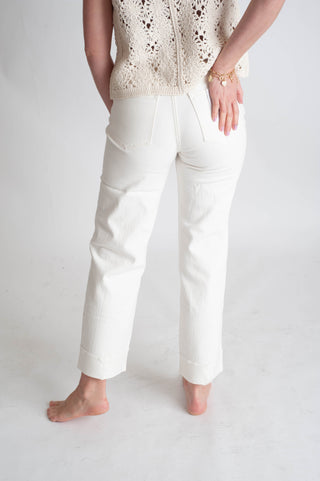 Person wearing white pants and a beige top on a plain background