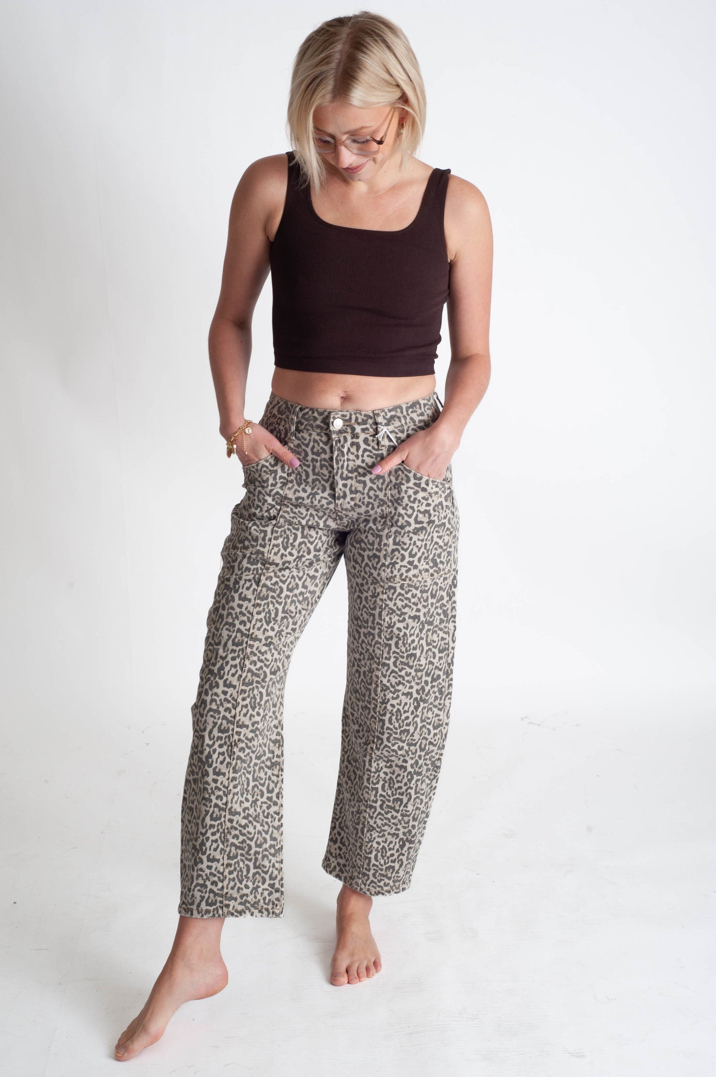 Woman wearing a black crop top and leopard pants on a white background