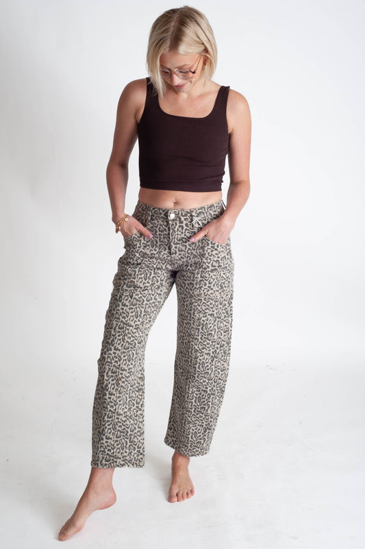 Woman wearing a black crop top and leopard pants on a white background